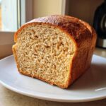 A close-up of a soft loaf of whole wheat bread, showing the light brown crumb texture.