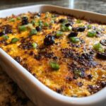 Close-up of hot, bubbly texas trash dip topped with melted cheese, black olives, and sliced green onions.