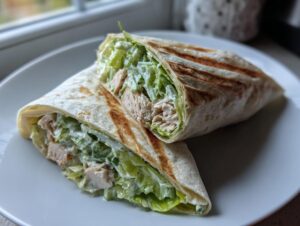 Two halves of a grilled tortilla filled with shredded chicken, crisp lettuce, and creamy dressing, showcasing the amazing chicken wraps.