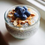 Close-up of creamy chia seed pudding topped with fresh blueberries and toasted sliced almonds.