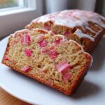 Close-up of a slice of Cinnamon Rhubarb Bread with Brown Butter, showing pink rhubarb pieces in the crumb and white glaze.