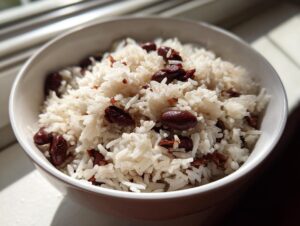 Close-up of a white bowl filled with fluffy white rice mixed with dark red kidney beans, representing creamy caribbean rice and beans.