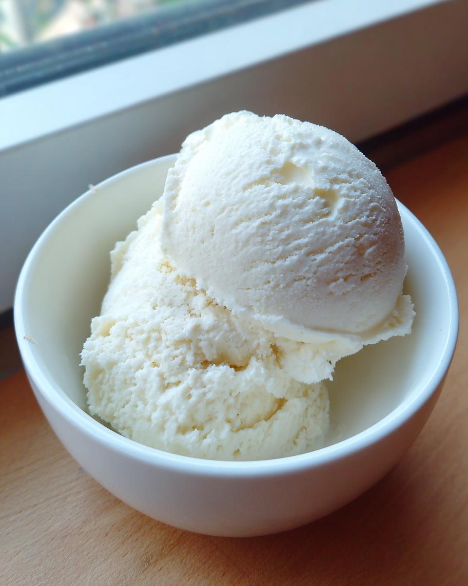 Two generous scoops of creamy, white cottage cheese ice cream served in a small white bowl.