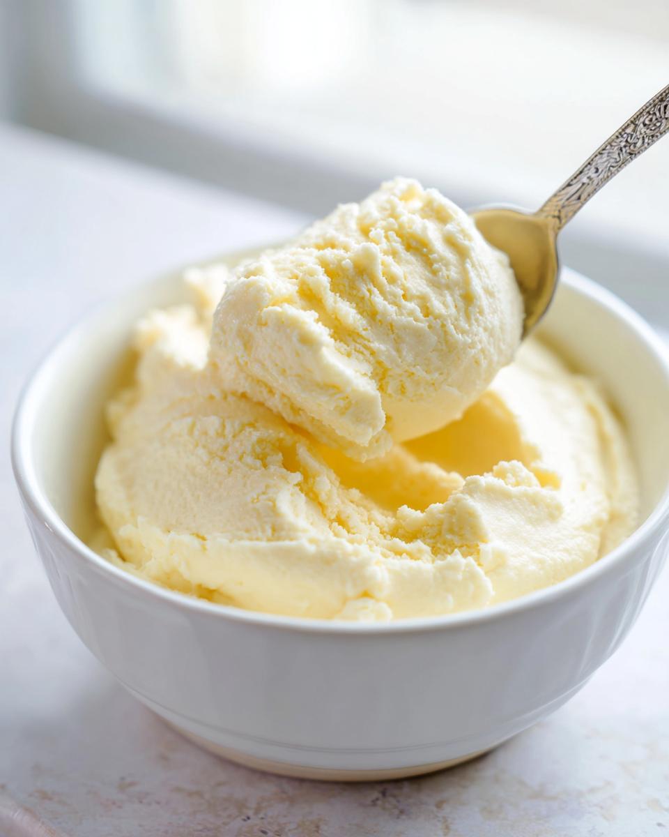 A spoonful of creamy, pale yellow homemade vanilla pudding being lifted from a white bowl.