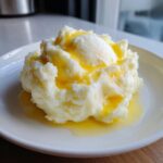 A serving of fluffy, creamy mashed potatoes topped with a melting pat of butter.