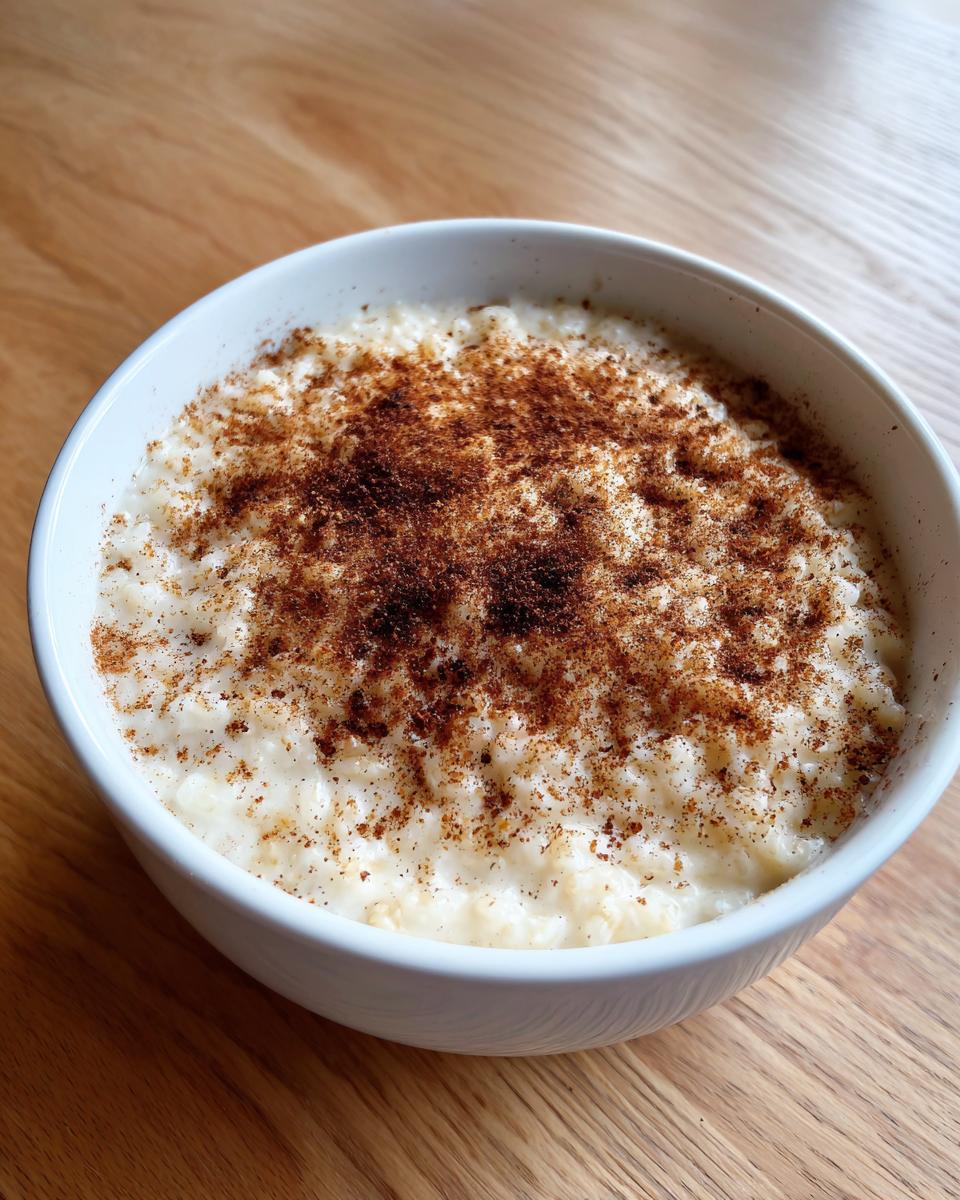 A white bowl filled with creamy rice pudding recipe topped generously with ground cinnamon.