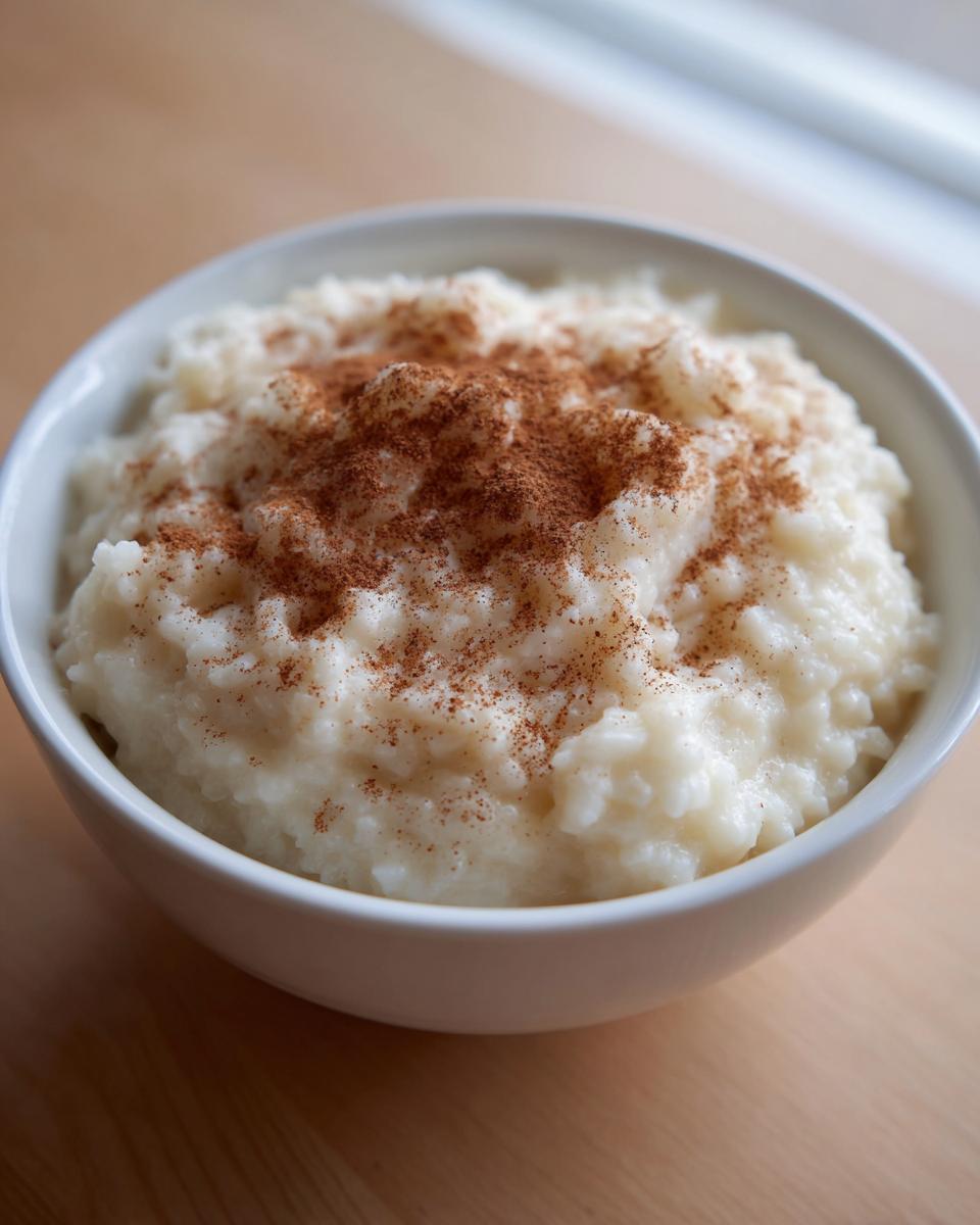 A white bowl filled with creamy rice pudding recipe, generously dusted with ground cinnamon.