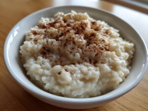 Close-up of a white bowl filled with creamy rice pudding recipe, generously sprinkled with ground cinnamon.