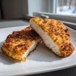 Two halves of crispy dill pickle chicken with parmesan twist, showing juicy white meat and golden brown crust.