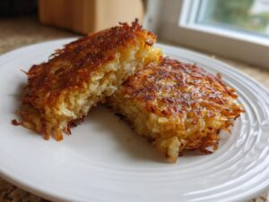 Two halves of a perfectly cooked, crispy hash browns recipe showing the shredded potato texture inside.