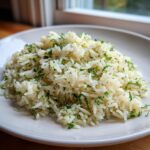 A mound of fluffy white greek rice seasoned and mixed with chopped fresh dill, served on a light plate.