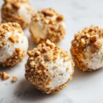 Close-up of several high protein frozen peanut butter greek yogurt bites coated in crushed peanuts.