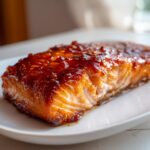 Close-up of a perfectly cooked fillet of hot honey glazed salmon with a shiny, dark amber glaze.