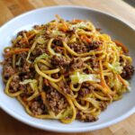 Close-up of a bowl filled with quick weeknight lo mein with ground beef, noodles, cabbage, and carrots.