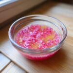 Close-up of vibrant pink Rhubarb and Shallot Vinaigrette with visible diced ingredients in a small glass bowl.