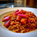 Close-up of a serving of Rhubarb-Lentil Curry featuring orange lentils and bright pink rhubarb pieces.