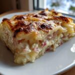 A close-up slice of creamy Rhubarb-Potato Gratin with Gruyère showing layers and a browned cheesy top.