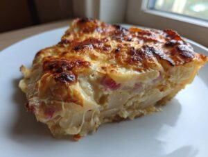 A close-up of a rich slice of Rhubarb-Potato Gratin with Gruyère, showing a golden-brown, cheesy top.
