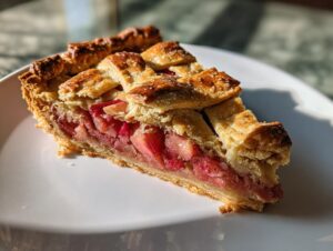 A close-up slice of Rustic Geometric Rhubarb Galette showing the bright pink rhubarb filling and golden, sugared lattice crust.