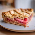 Close-up of a slice of Rustic Geometric Rhubarb Galette showing flaky crust and bright pink rhubarb filling.