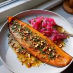 A fillet of Smoked Trout with Brown Butter and Rhubarb, topped with chopped nuts and herbs, served with pickled pink rhubarb.