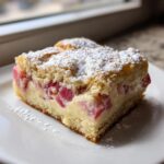 A close-up of a square slice of Sour Cream Rhubarb Squares with Lemon, topped with powdered sugar.