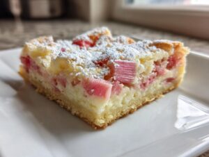 Close-up of a single serving of Sour Cream Rhubarb Squares with Lemon, topped with powdered sugar.