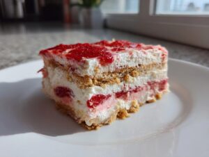 A perfect slice of strawberry dream dessert showing layers of cream, strawberries, and biscuit base on a white plate.