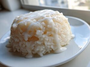 A perfectly molded serving of fluffy thai coconut rice drizzled generously with sweet coconut cream sauce.