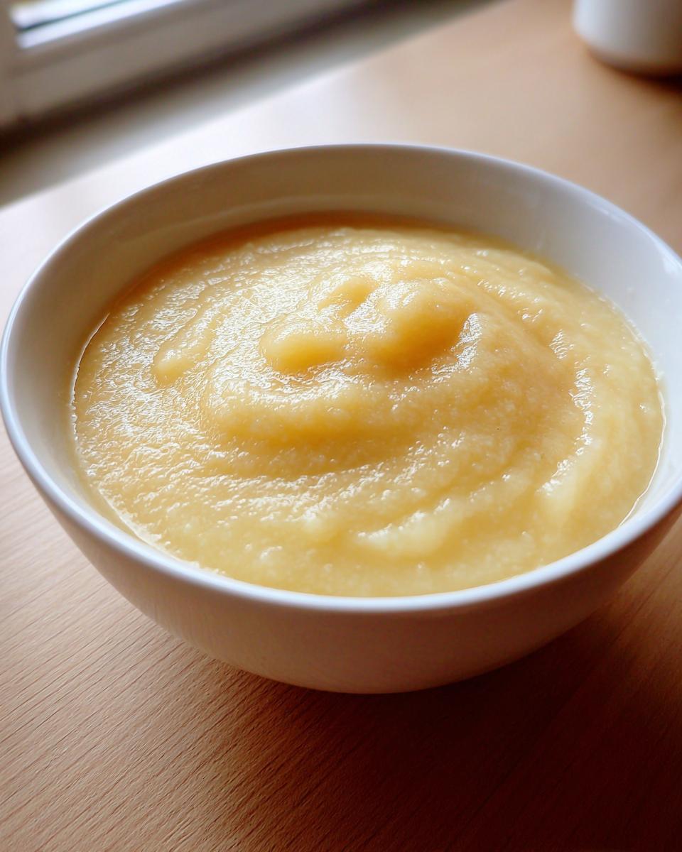 Close-up of a white bowl filled with thick, creamy, light yellow low calorie potato soup.