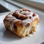Close-up of a soft, freshly baked protein cinnamon rolls drizzled generously with white icing.